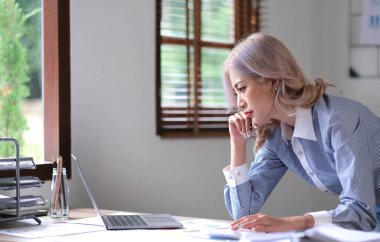 Genç Asyalı kadın migren ağrısı çekiyor. Ofiste dizüstü bilgisayarla çalışırken çok çalışan iş kadını finansörü.