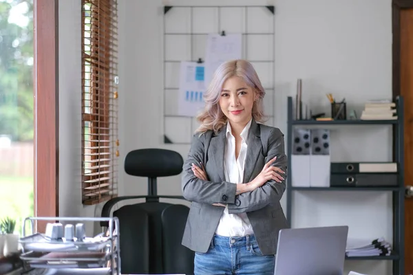 Young confident smiling Asian business woman leader, successful entrepreneur, elegant professional company executive ceo manager. Asian business woman is standing in office with arms crossed