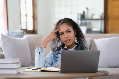 Üniversite derslerinden dolayı başı ağrıyan yorgun bir kız öğrencinin internet sitelerine girmek için kablosuz internet bağlantısı var. Klapadan öğrenmekten bıkmış, koyu tenli mutsuz bir kadın.