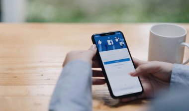 Chiang Mai Tayland. 2022 yılının ortalarında. Kadın ekranında facebook uygulaması olan akıllı bir telefon tutuyor. Facebook akıllı telefon için fotoğraf paylaşım uygulamasıdır