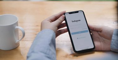CHIANG MAI, THAILAND - 26 AUG 2022: Bir kadın Kafe 'deki ekranda Apple iPhone X uygulamasını tutuyor. Instagram akıllı telefonlar için fotoğraf paylaşım uygulamasıdır