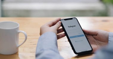 CHIANG MAI, THAILAND - 26 AUG 2022: Bir kadın Kafe 'deki ekranda Apple iPhone X uygulamasını tutuyor. Instagram akıllı telefonlar için fotoğraf paylaşım uygulamasıdır
