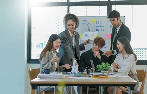 Asian business woman leader in a meeting with her multi-ethnic colleagues at the office presenting sales data or forecast for a projec