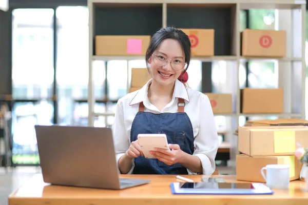 Startup SME small business entrepreneur of freelance Asian woman using a calculator with box Cheerful success happy Asian woman her hand lifts up online marketing packaging and delivery SME idea concep