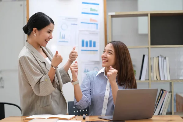 Happy business asian people are keeping arms raised hi five and expressing joyful while standing. achieving goals