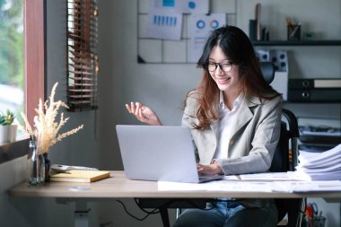 Asyalı iş kadını dizüstü bilgisayar kullanıyor ve ofiste hesap makinesi ile çalışıyor, mali raporu, iş planı yatırımını, mali analiz konseptini analiz etmeyi planlıyor.