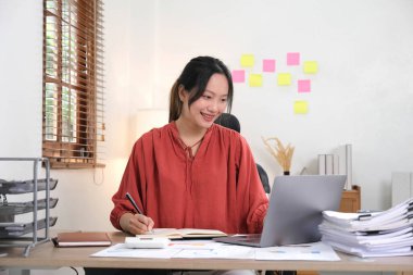 Ofisinde dizüstü bilgisayar ya da defter üzerinde çalışan genç bir kadın. Güzel Freelancer Kadını evinde çalışıyor. Güzel Asyalı iş kadını konsepti
