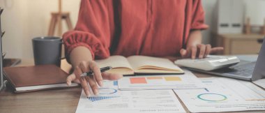 Hesap makinesi ve dizüstü bilgisayar kullanan iş kadını ofis ve iş geçmişinde, vergi, muhasebe, istatistik ve analitik araştırma kavramında ahşap masada finans yapıyor..
