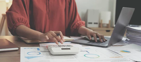 Business woman using calculator for do math finance on wooden desk in office and business working background, tax, accounting, statistics and analytic research concept.