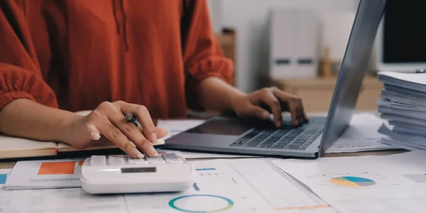 Hesap makinesi ve dizüstü bilgisayar kullanan iş kadını ofis ve iş geçmişinde, vergi, muhasebe, istatistik ve analitik araştırma kavramında ahşap masada finans yapıyor..