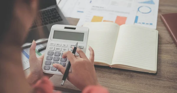 Business woman using calculator for do math finance on wooden desk in office and business working background, tax, accounting, statistics and analytic research concept.