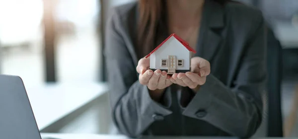 architecture, building, construction, real estate and property concept - close up of hands holding house or home model.