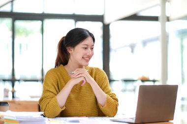 Asyalı iş kadını dizüstü bilgisayar kullanıyor ve ofiste hesap makinesi ile çalışıyor, mali raporu, iş planı yatırımını, mali analiz konseptini analiz etmeyi planlıyor...