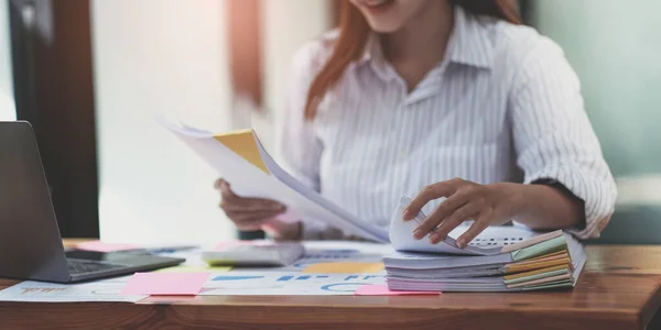 Business Documents concept : Employee woman hands working in Stacks paper files for searching and checking unfinished document achieves on folders papers at busy work desk office. Soft focus.