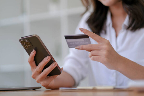 Close up. woman holding smartphone and using credit card for online shopping..