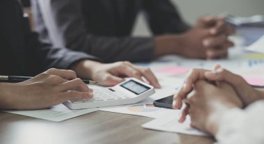 Ticari veri özeti raporunu, muhasebe belgesini ve ofisteki dizüstü bilgisayarı, iş toplantısı kavramını hesaplamak için hesap makinesiyle çalışan bir muhasebeci...