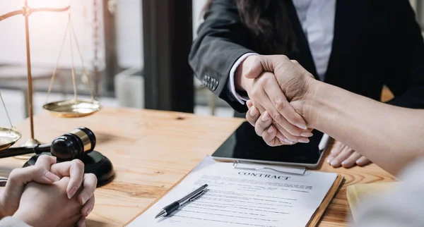 Close up of woman lawyer hand and man client shaking hand collaborate on working agreements with contract documents at the office..