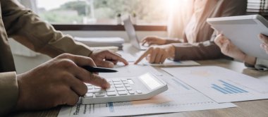 Finans, vergi, muhasebe, istatistik ve analitik araştırma konseptini hesaplamak için hesap makinesi ve dizüstü bilgisayar kullanarak iş adamı ve ortağını kapat.