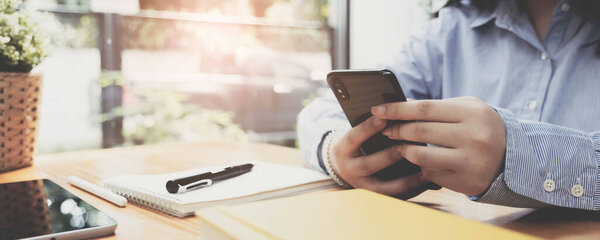 Закройте руку женщине, пользующейся смартфоном в кафе.