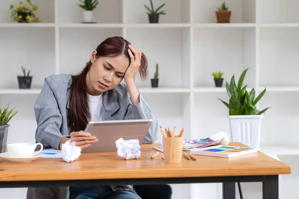 Stressed Asian businesswoman unsatisfied with her work, using portable tablet to check her email, receiving a bad email from her boss, getting a complained from customer..