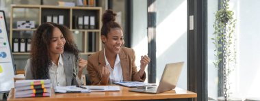 Two young Asian business woman talk, consult, discuss working with new startup project idea presentation analyze plan marketing and investment in the office..