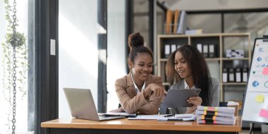 Two young Asian business woman talk, consult, discuss working with new startup project idea presentation analyze plan marketing and investment in the office..
