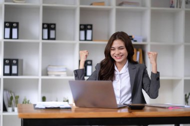 Pretty Asian businesswoman sitting on a laptop And the work came out successfully and the goal was achieved, happy and satisfied with her..