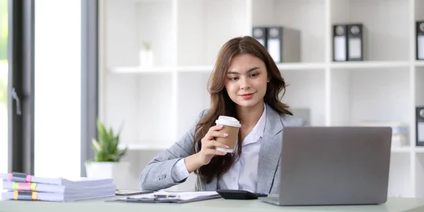 Young woman working on a laptop in the office. Asian businesswoman sitting at her workplace in the office. Beautiful Freelancer Woman working online