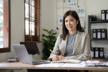 Bir ofis masası, vergi, rapor, muhasebe, istatistik ve analitik araştırma kavramında matematik finansmanı için hesap makinesi ve dizüstü bilgisayar kullanan Asyalı İş kadını.