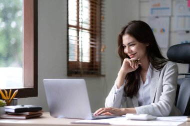 Ofiste dizüstü bilgisayarda çalışan genç bir kadın. Ofisteki iş yerinde oturan Asyalı iş kadını. Güzel Freelancer Kadını evinde çalışıyor.
