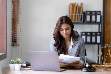 Thinking woman lawyers discussing contract papers with brass scale in office. Law, legal services, advice, Justice and real estate concept..