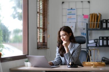 Hukuk bürosunda dizüstü bilgisayarla çalışan Asyalı avukat kadın. Hukuki ve hukuki hizmet kavramı