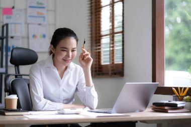 Bir ofis masası, vergi, rapor, muhasebe, istatistik ve analitik araştırma kavramında matematik finansmanı için hesap makinesi ve dizüstü bilgisayar kullanan Asyalı İş kadını.