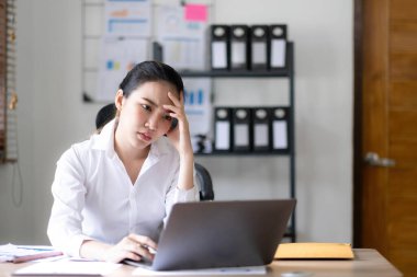 Asyalı bir kadın online problem çözümü hakkında çok endişeli. Laptop ekranına bakıyor. Asyalı ciddi iş kadını zor bir bilgisayar işini çözmeye odaklanmış...