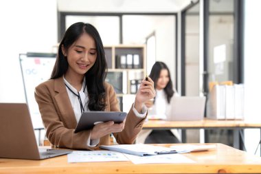 Bir ofis masası, vergi, rapor, muhasebe, istatistik ve analitik araştırma kavramında matematik finansmanı için hesap makinesi ve dizüstü bilgisayar kullanan Asyalı İş kadını.