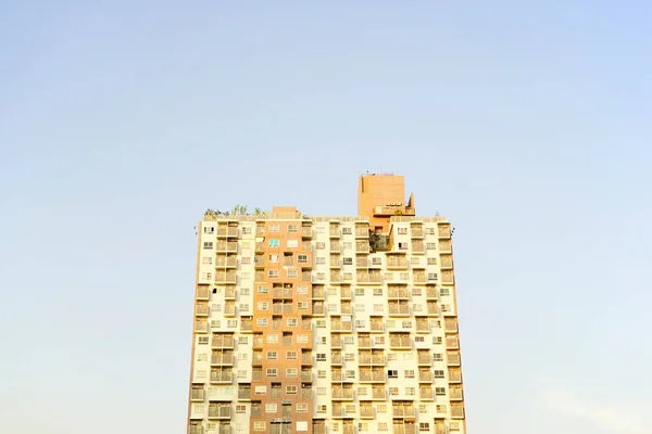 Kentsel apartman dairesi, modern düz kozmopolit konut yapısına karşı pastel mavi eğimli ufuk çizgisi arkaplanı.