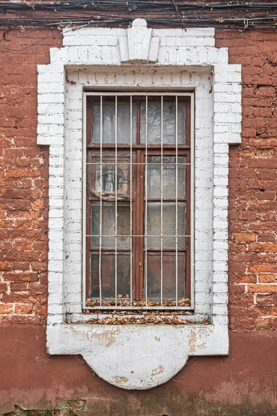 用白色粉刷过的砖头装饰过的窗玻璃和旧砖房里的棕色木架 房子的窗台上撒满了秋天的落叶 — 图库照片