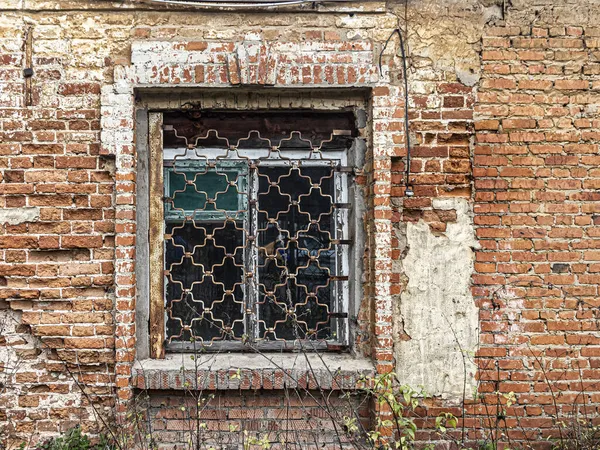 窗上有一个图形格子在墙壁上的旧的半废弃的房子 湿透了的砖块 — 图库照片