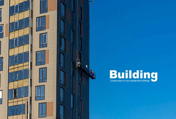 作業員のチームは 建物と青空のファサードの背景を背景に 高さのある建設クレードルで自分の仕事を実行します テキスト挿入の背景 — ストック写真
