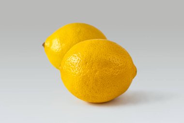 Açık arkaplanda kalın, gözenekli, sarı derili olgun ve sulu limonlar.