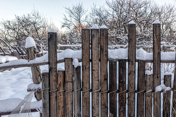 Dilapidated wooden fence with a snow cap after a heavy snowfall