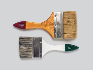 Boya onarımı için sert kıllı iki boya fırçası açık bir arkaplan üzerinde çalışıyor.