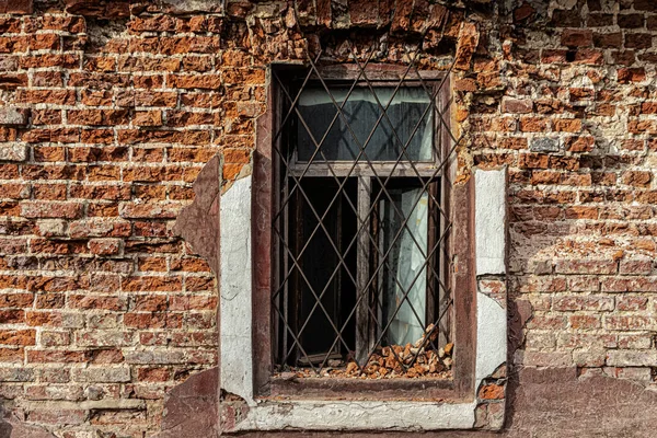 废弃房屋的旧砖墙上有锈迹斑斑的格栅窗 — 图库照片