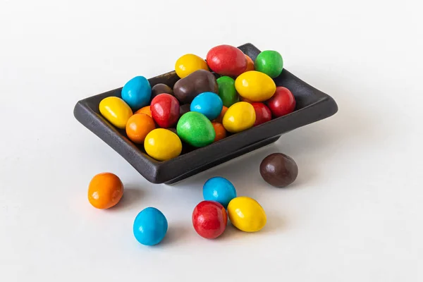 薄い背景にセラミック長方形のプレートに多色の丸いキャンディー — ストック写真