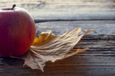 Eski ahşap arka planda elma ve sarı sonbahar yaprağı