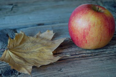 Eski ahşap arka planda elma ve sarı sonbahar yaprağı