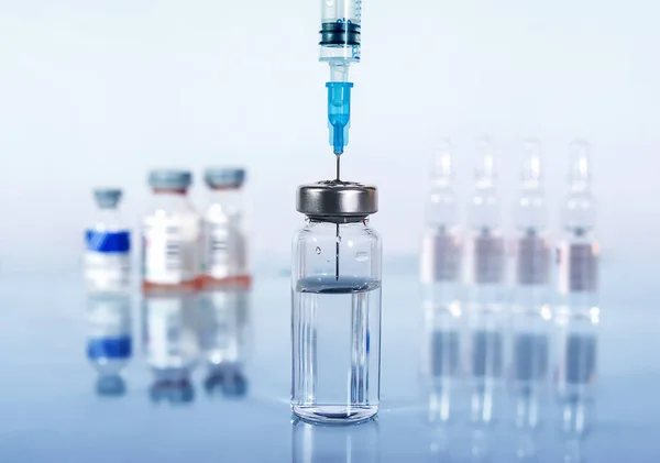 Şırınga ve farklı türde ampul ve şişeler beyaz arkaplandaki yansıma ile yakın plan