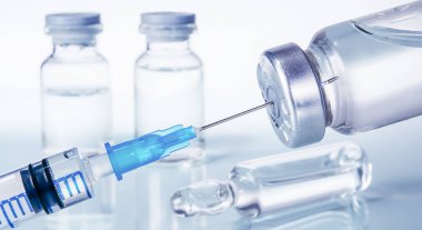 Şırınga ve farklı türde ampul ve şişeler beyaz arkaplandaki yansıma ile yakın plan