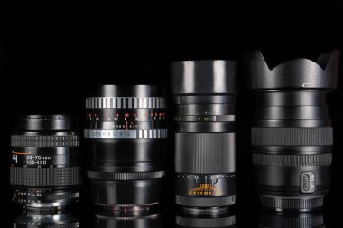 Modern ve eski DSLR kamera lensleri siyah arkaplanı yansıtmalı olarak ayarlandı