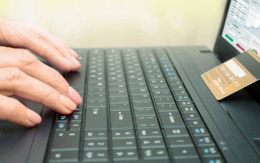 Not defteri, kredi kartı ve elleri dizüstü bilgisayarda. E-ticaret, elektronik ödemeler ve uzaktan çalışma kavramı